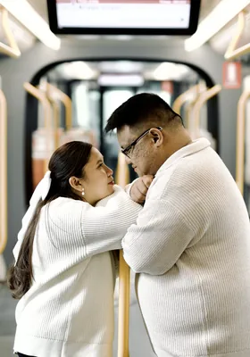 Face to face, holding on to the rail of an empty light rail carriage.
