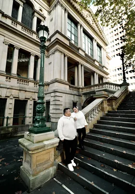 Resting against a green lamp post on a sandstone staircase in the city.