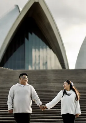 Holding hands on the wide steps below the Opera House sails.