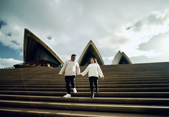 Running up the Opera House steps together under a heavy sky.